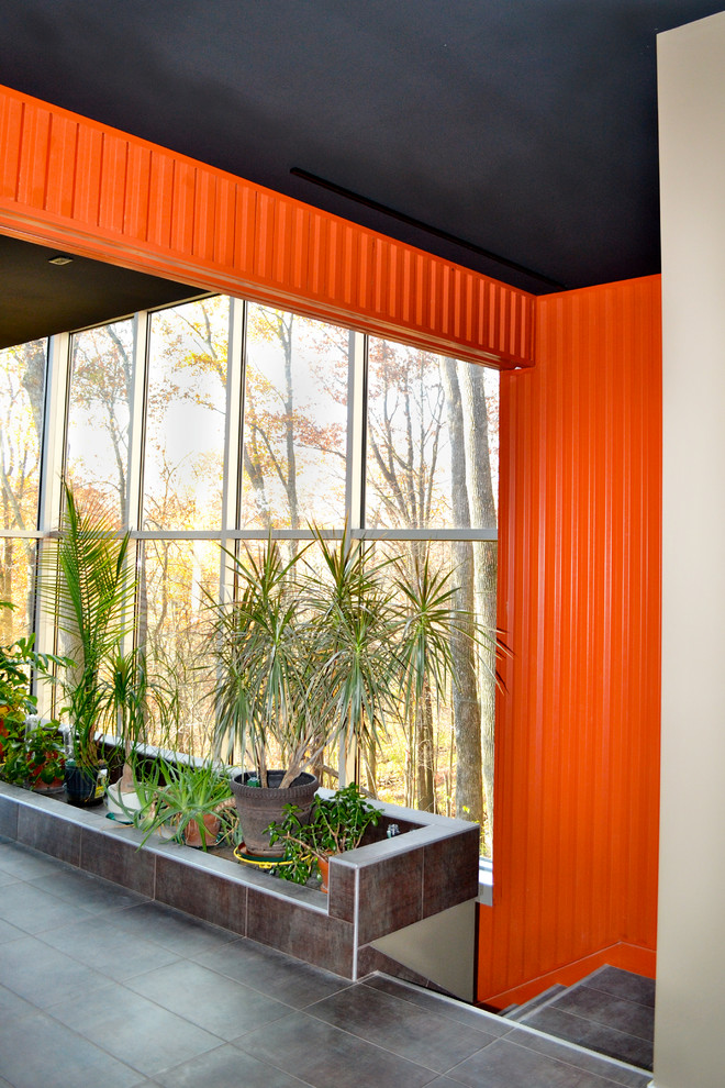 На фото: большой коридор в современном стиле с оранжевыми стенами и полом из керамогранита с