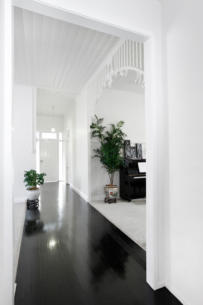 Cette photo montre un couloir tendance de taille moyenne avec un mur blanc, parquet foncé et un sol noir.