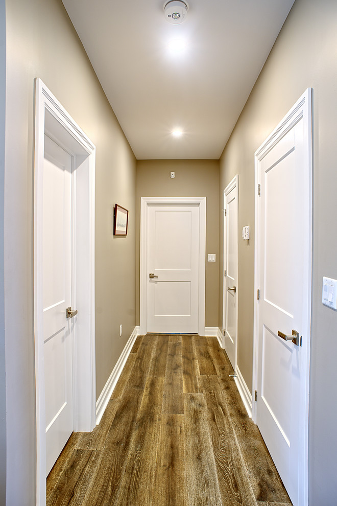 Réalisation d'un couloir minimaliste de taille moyenne avec un mur beige, un sol en bois brun et un sol marron.