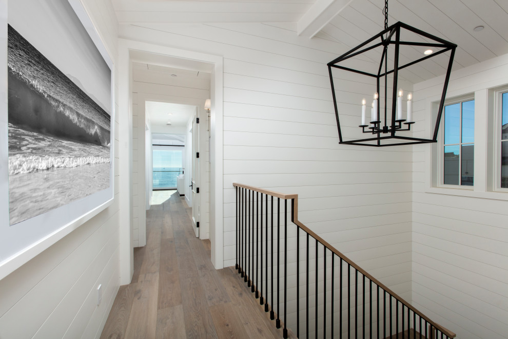 Hallway - large coastal medium tone wood floor and brown floor hallway idea in Los Angeles with white walls