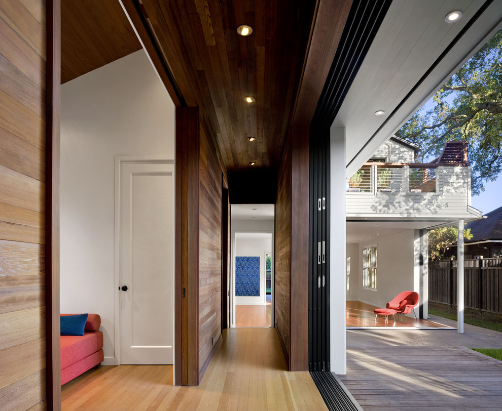Diseño de recibidores y pasillos contemporáneos con paredes blancas y suelo de madera en tonos medios