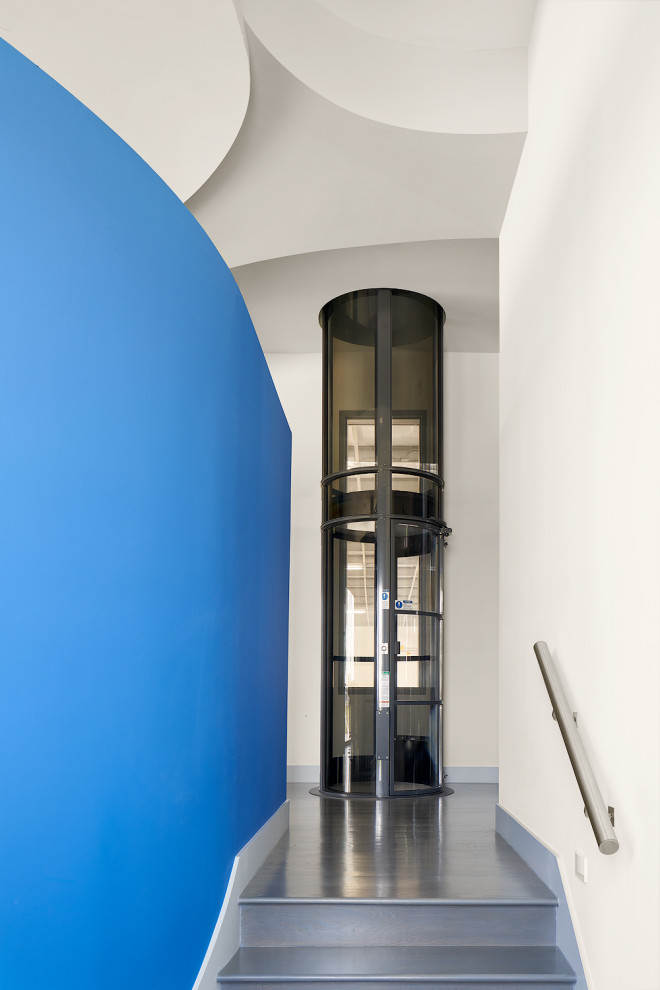 Idée de décoration pour un très grand couloir minimaliste avec un mur bleu, un sol en bois brun et un sol gris.