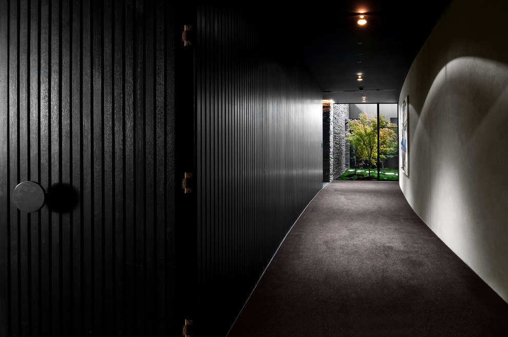 Immagine di un grande ingresso o corridoio minimal con pareti nere, moquette e pavimento nero