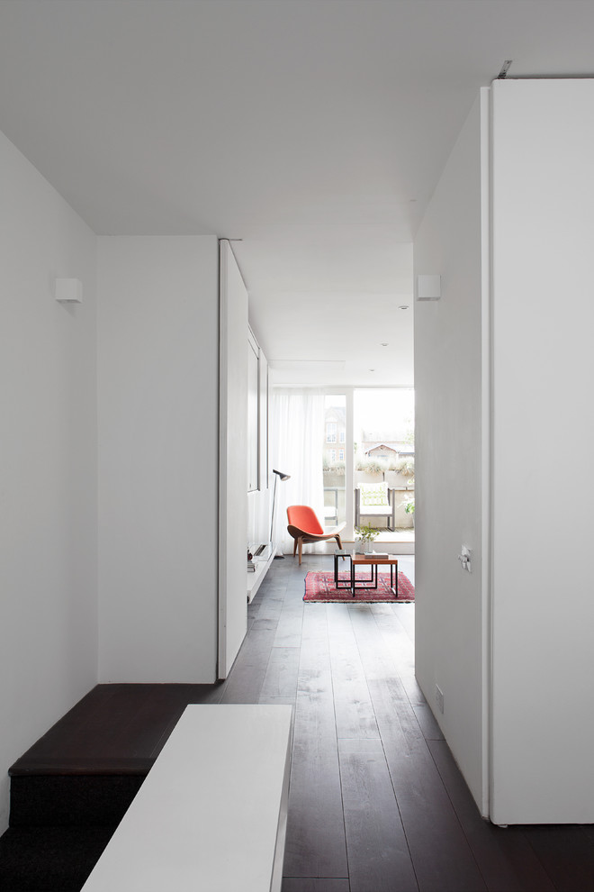 Example of a mid-sized trendy dark wood floor hallway design in London with white walls