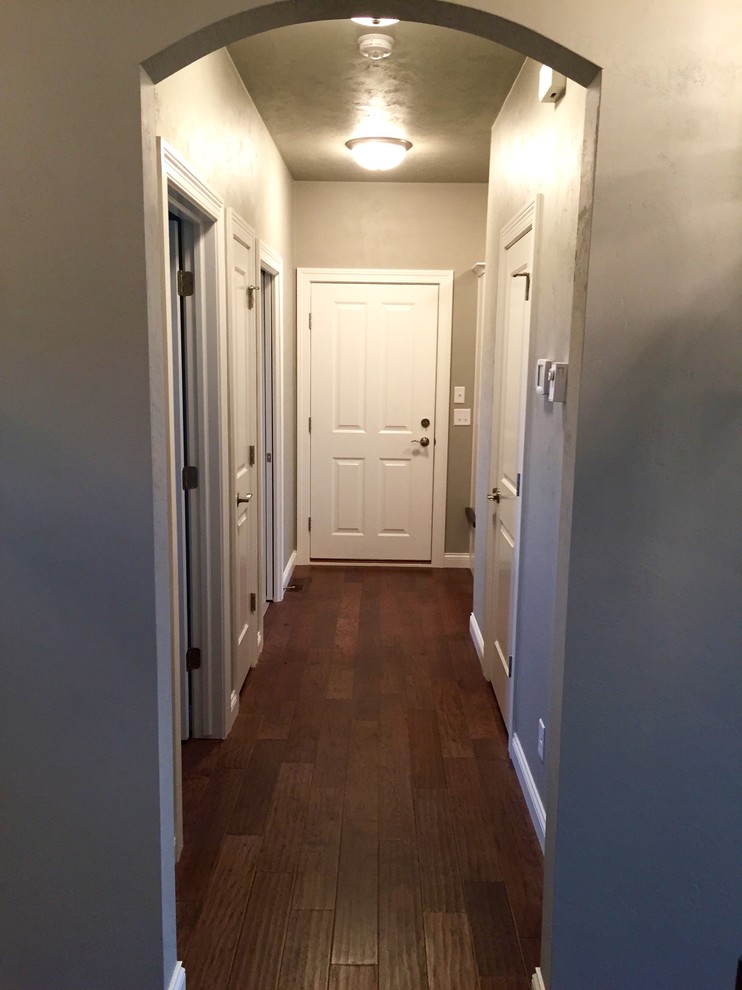 Cette image montre un couloir craftsman de taille moyenne avec un mur gris et un sol en bois brun.