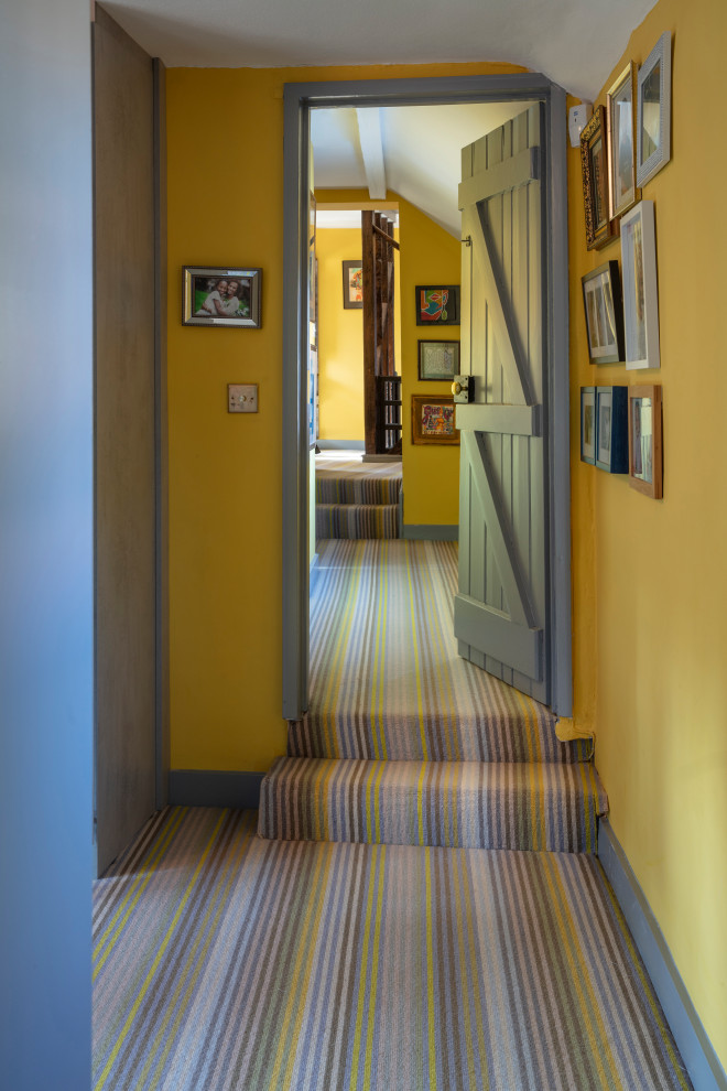 Eclectic carpeted and yellow floor hallway photo in London