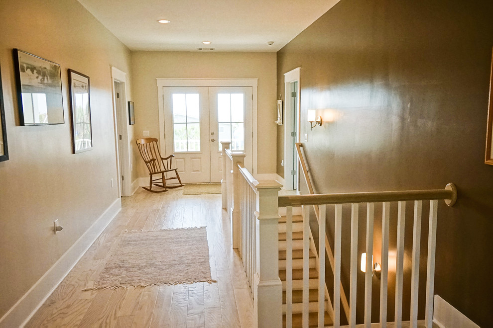 Example of a large beach style light wood floor hallway design in Atlanta with beige walls
