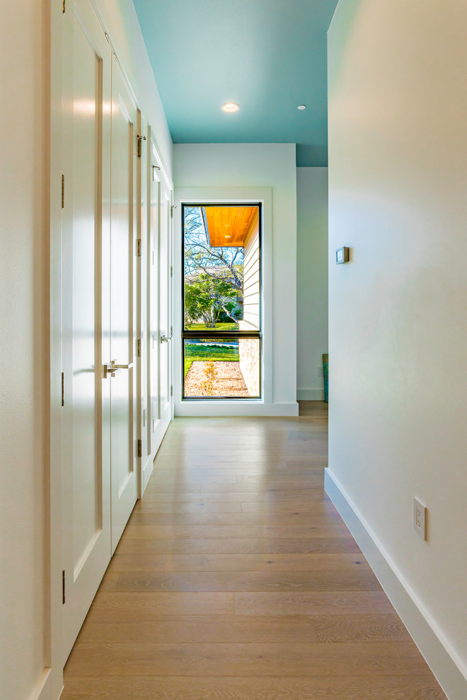 Idée de décoration pour un grand couloir design avec un mur blanc, parquet clair et un sol marron.