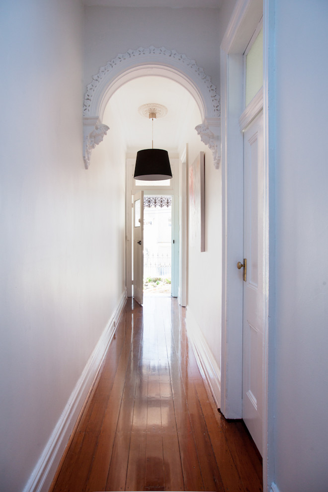 На фото: коридор в стиле неоклассика (современная классика) с белыми стенами и паркетным полом среднего тона