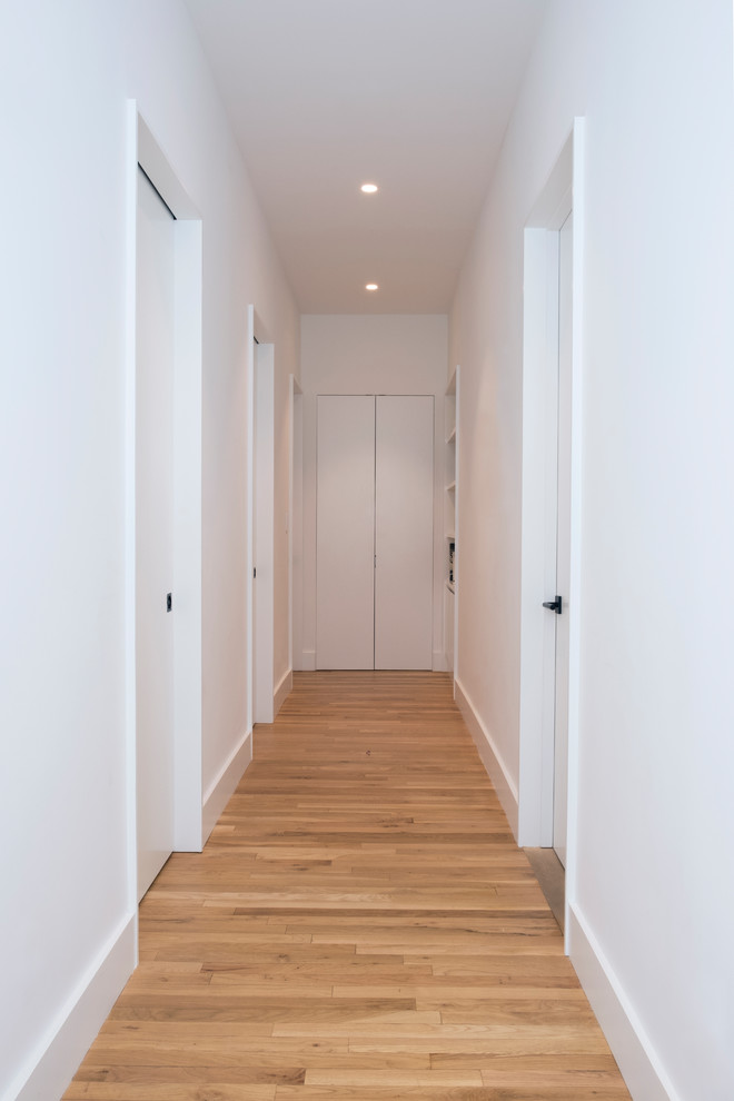 Esempio di un ingresso o corridoio design di medie dimensioni con pareti bianche, parquet chiaro e pavimento marrone