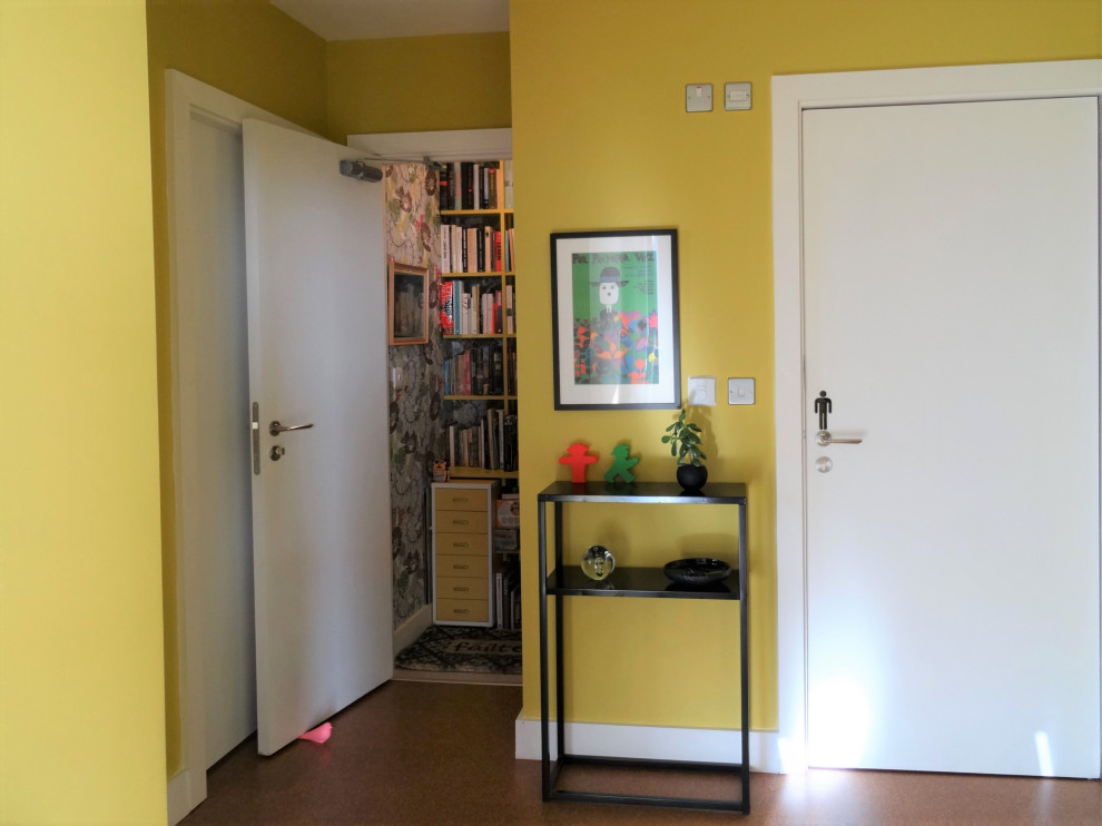Cette photo montre un couloir éclectique de taille moyenne avec un mur jaune, un sol en liège et un sol marron.