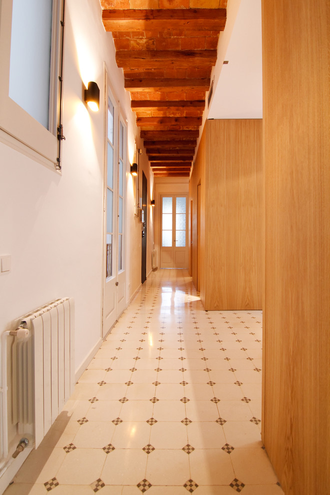 На фото: большой коридор в стиле фьюжн с белыми стенами и полом из известняка с