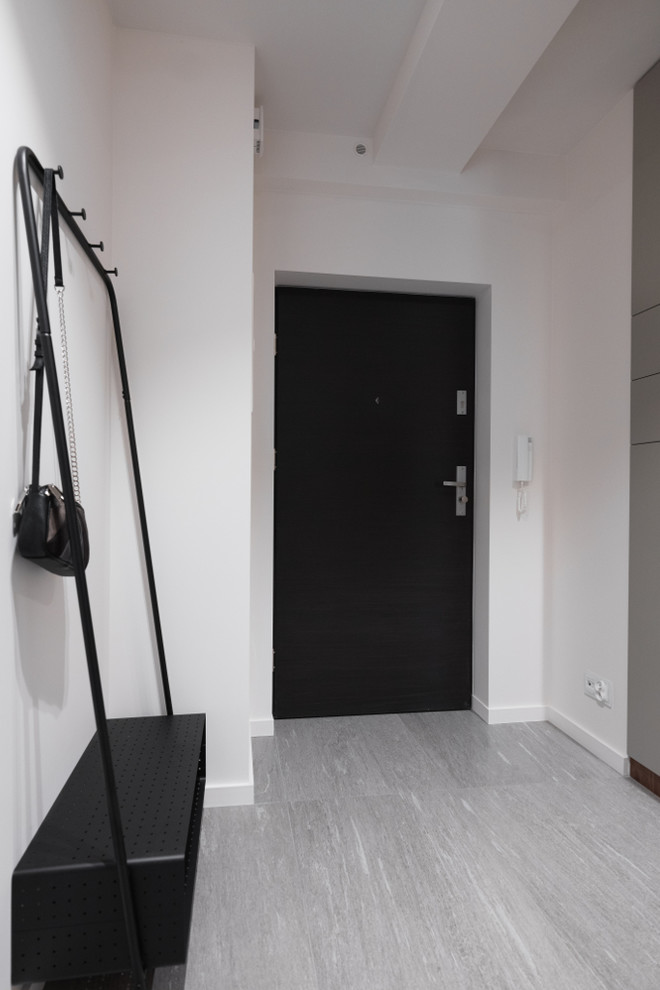Cette image montre un petit couloir bohème avec un mur blanc, un sol en carrelage de céramique et un sol gris.