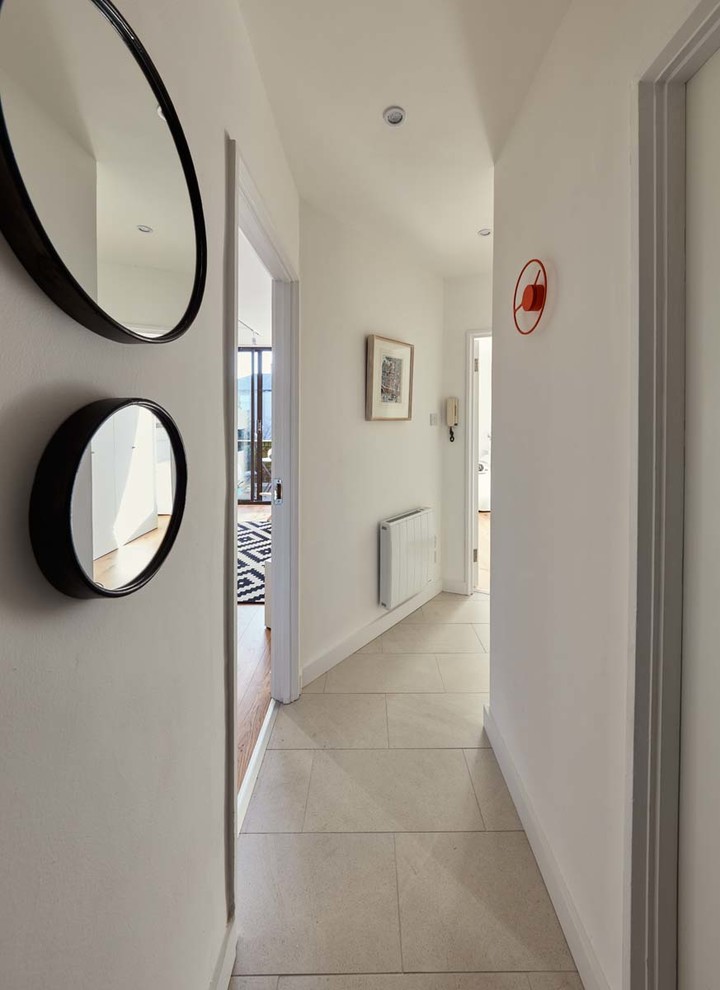 На фото: коридор среднего размера в современном стиле с белыми стенами и полом из керамической плитки с