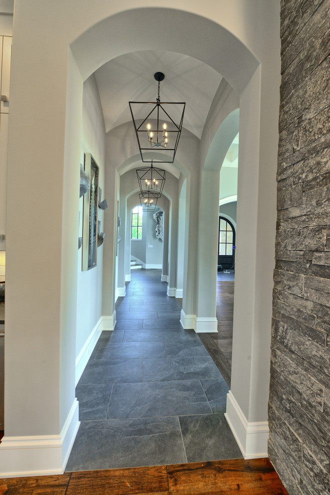 Idées déco pour un couloir avec un mur gris, un sol en carrelage de céramique, un sol gris et un plafond voûté.