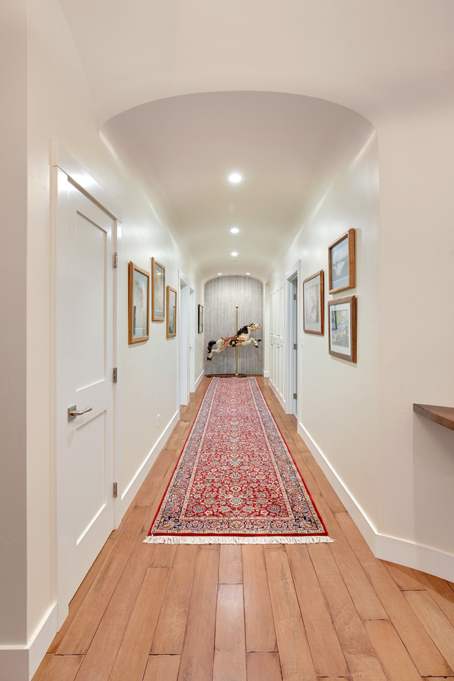 Immagine di un ampio ingresso o corridoio american style con pareti bianche e pavimento in legno massello medio