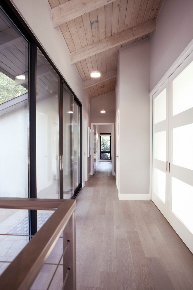 На фото: большой коридор в стиле модернизм с серыми стенами, светлым паркетным полом и коричневым полом с