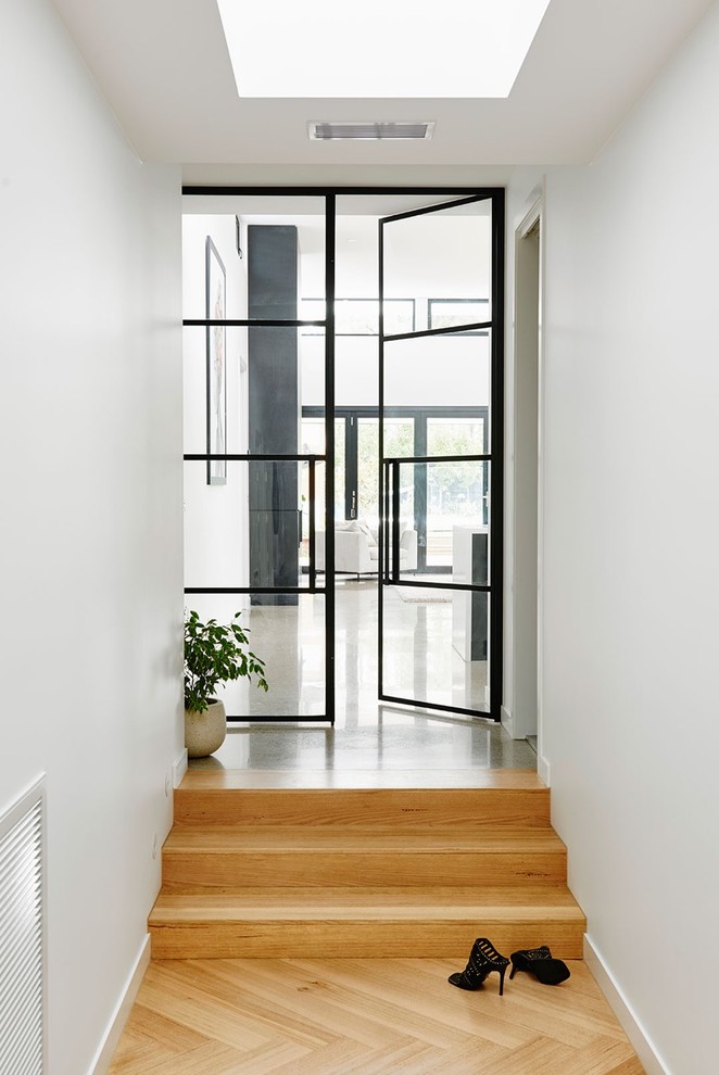 Aménagement d'un couloir moderne avec un mur blanc et parquet clair.