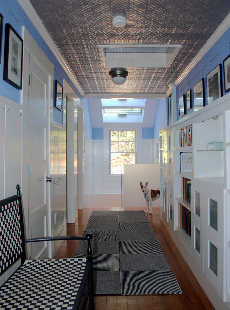 Cette photo montre un couloir chic avec un mur blanc et un sol en bois brun.