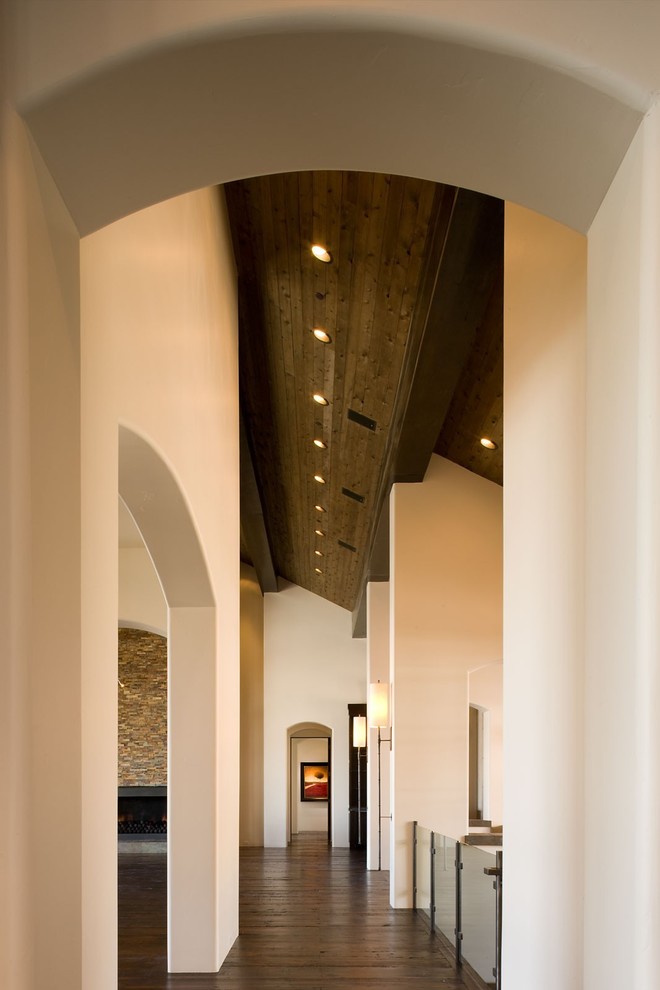 Cette photo montre un grand couloir moderne avec un mur beige et parquet foncé.