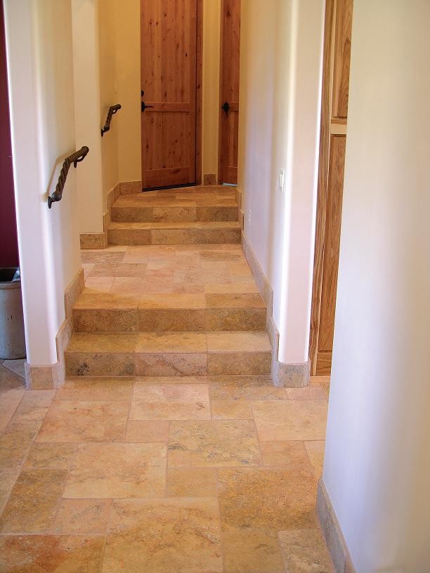 Cette image montre un petit couloir traditionnel avec un mur blanc et un sol en travertin.