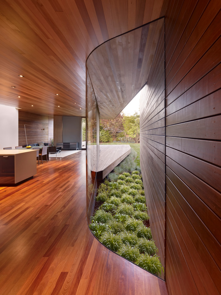 Aménagement d'un grand couloir moderne avec un sol en bois brun et un mur marron.