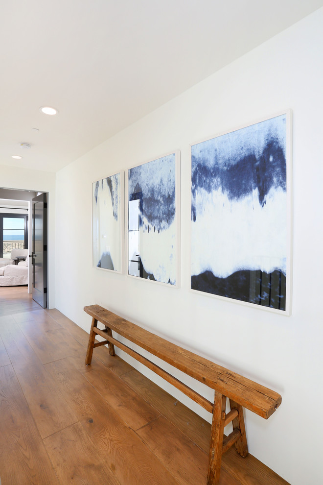 Example of a beach style medium tone wood floor hallway design in Orange County with white walls