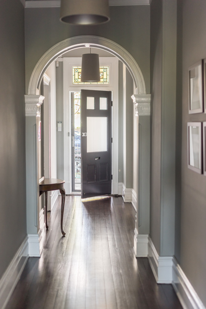Пример оригинального дизайна: большой коридор в викторианском стиле с серыми стенами, темным паркетным полом и коричневым полом
