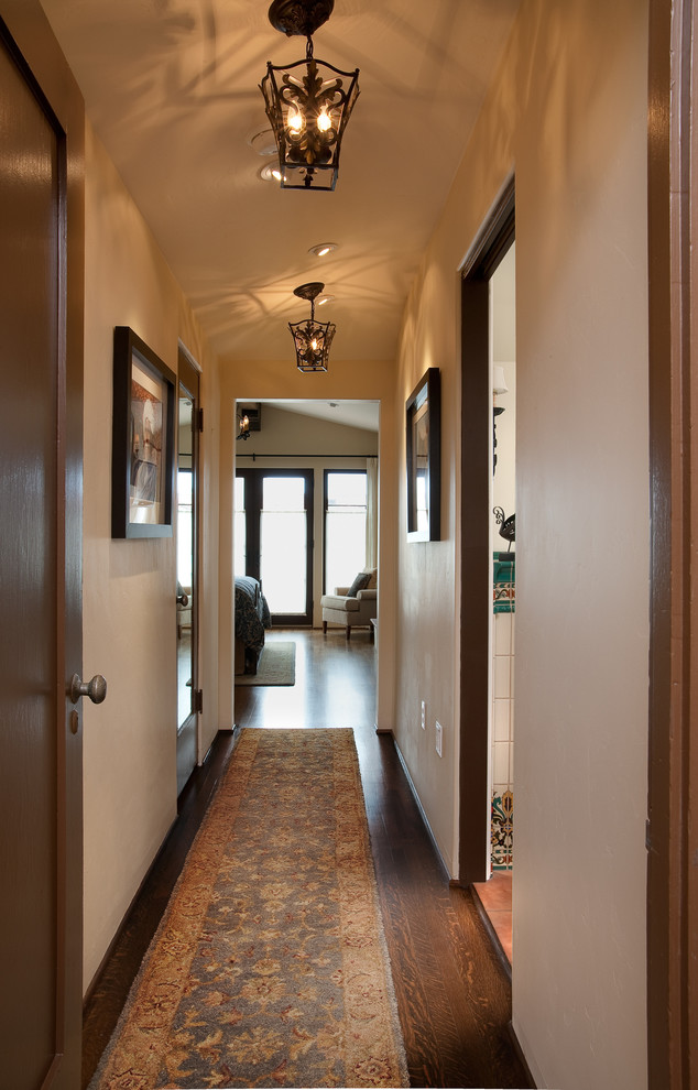Hallway - mediterranean dark wood floor hallway idea in San Diego with beige walls