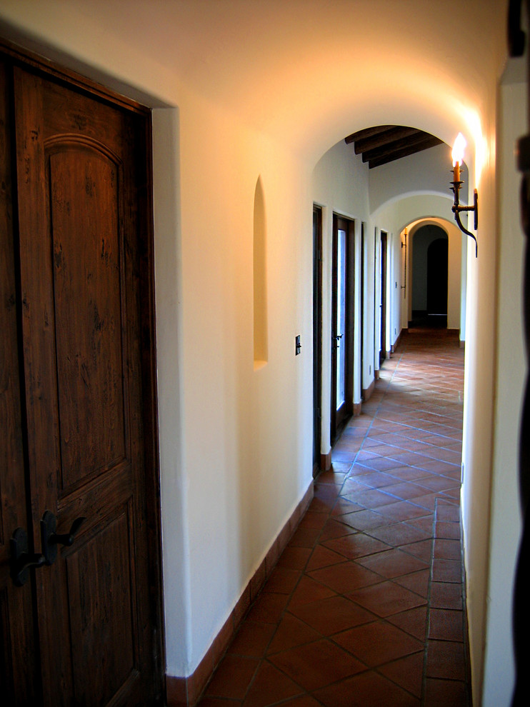 Стильный дизайн: коридор среднего размера в средиземноморском стиле с белыми стенами, полом из терракотовой плитки и красным полом - последний тренд