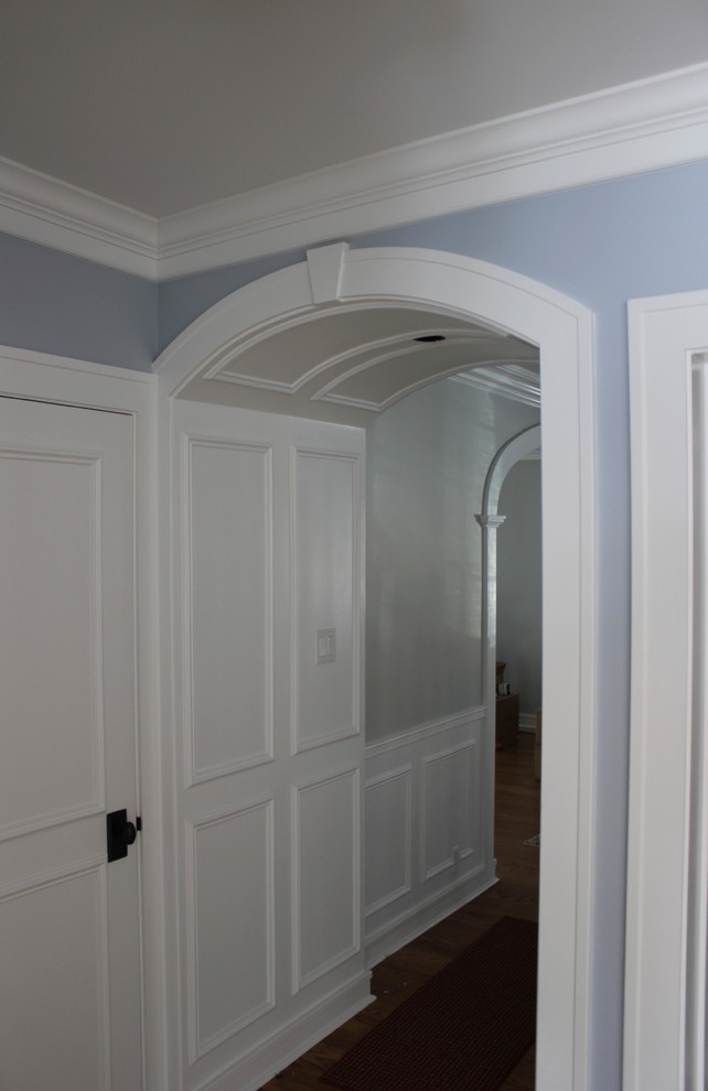 Example of a mid-sized classic dark wood floor, brown floor and wainscoting hallway design in Chicago with blue walls