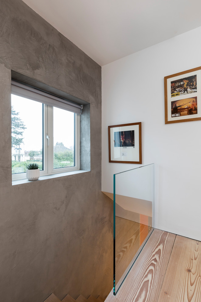Cette image montre un couloir minimaliste de taille moyenne avec un mur gris, parquet peint et un sol blanc.