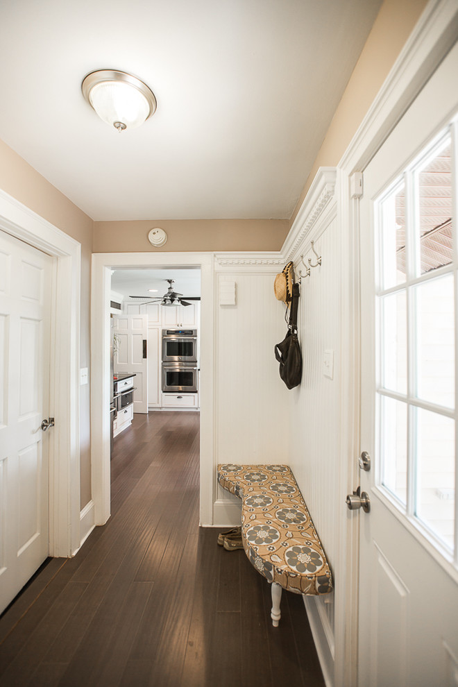 Cette image montre un petit couloir vintage avec un mur beige et un sol marron.
