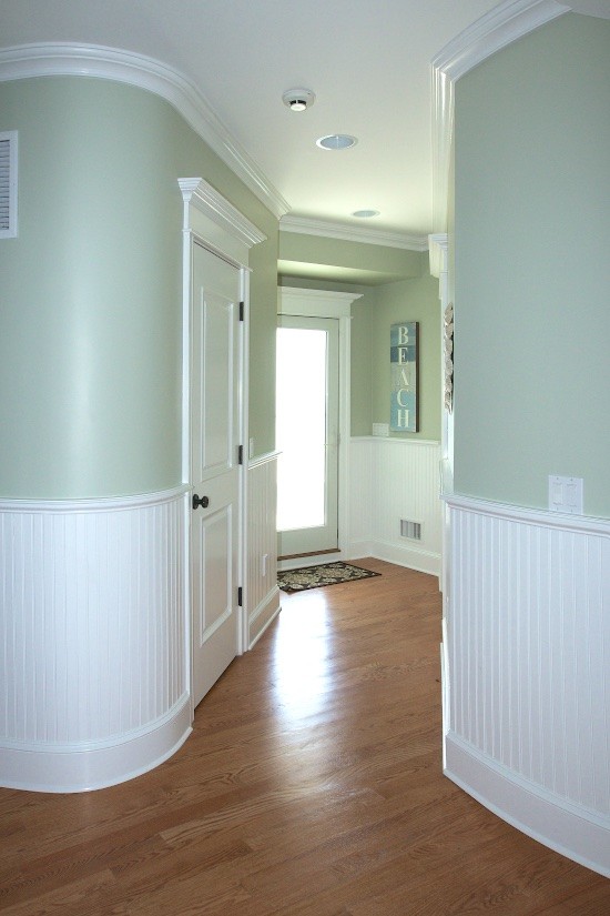 Large beach style light wood floor hallway photo in New York with green walls