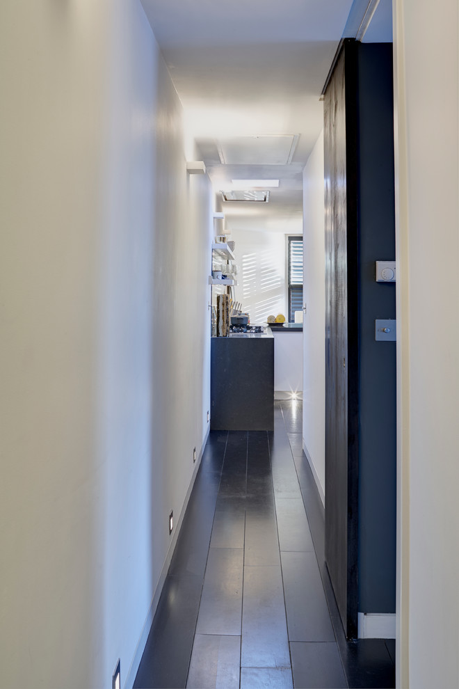 Idee per un piccolo ingresso o corridoio design con pareti bianche, parquet scuro e pavimento nero