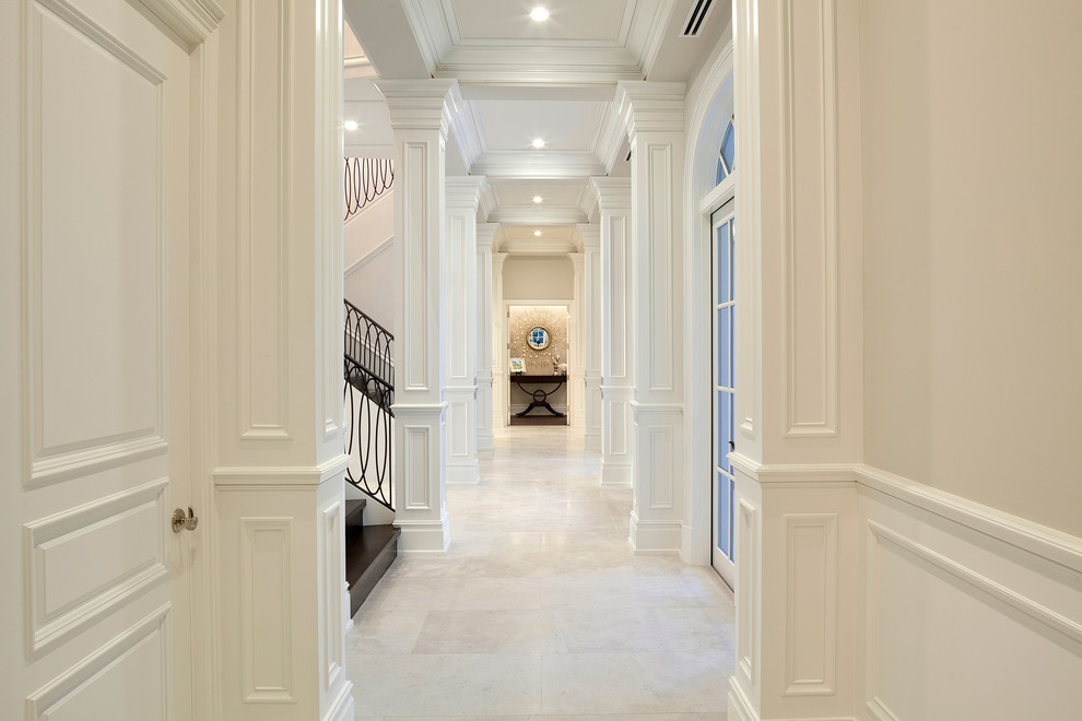 Aménagement d'un très grand couloir avec un mur beige, un sol en marbre et un sol beige.