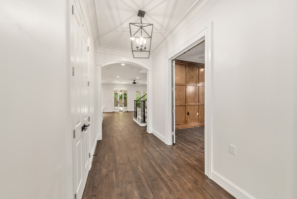 Стильный дизайн: коридор среднего размера в стиле неоклассика (современная классика) с белыми стенами, полом из ламината и коричневым полом - последний тренд