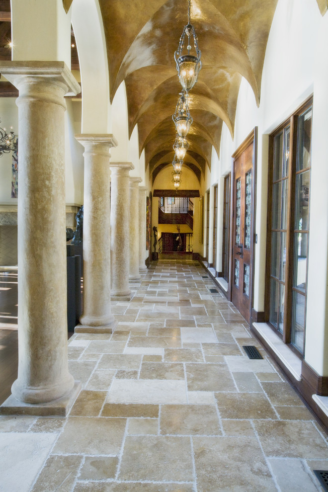 Ejemplo de recibidores y pasillos mediterráneos con paredes blancas y suelo de travertino