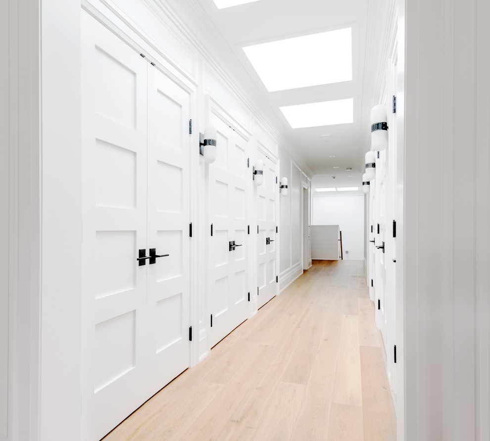 Idées déco pour un couloir contemporain de taille moyenne avec un mur blanc, un sol en bois brun et un sol marron.