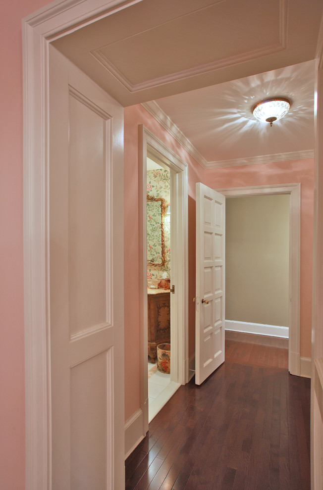 На фото: коридор среднего размера в стиле неоклассика (современная классика) с розовыми стенами и темным паркетным полом с