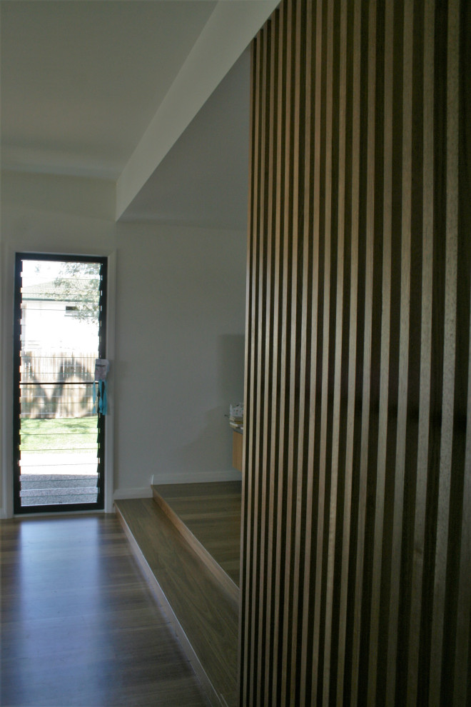 Modelo de recibidores y pasillos contemporáneos con paredes blancas y suelo de madera en tonos medios