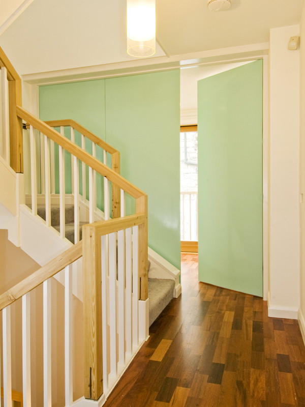 Réalisation d'un petit couloir design avec un mur blanc et un sol en bois brun.