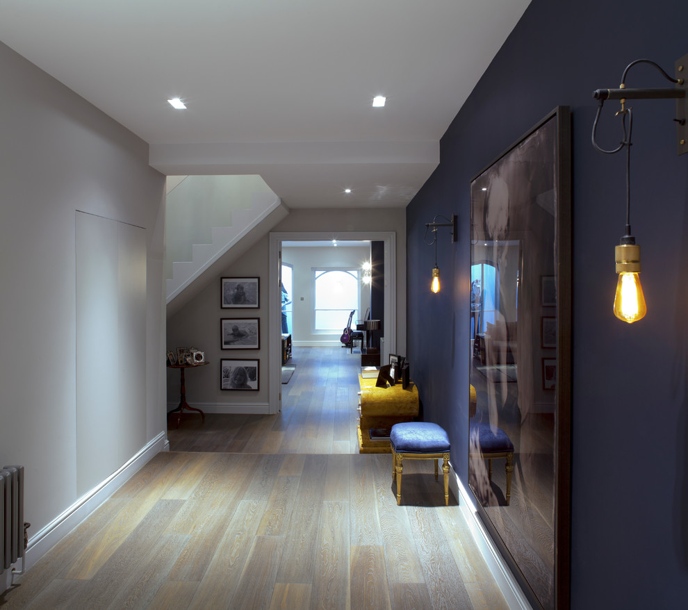 Idées déco pour un couloir contemporain de taille moyenne avec un mur bleu et un sol en bois brun.