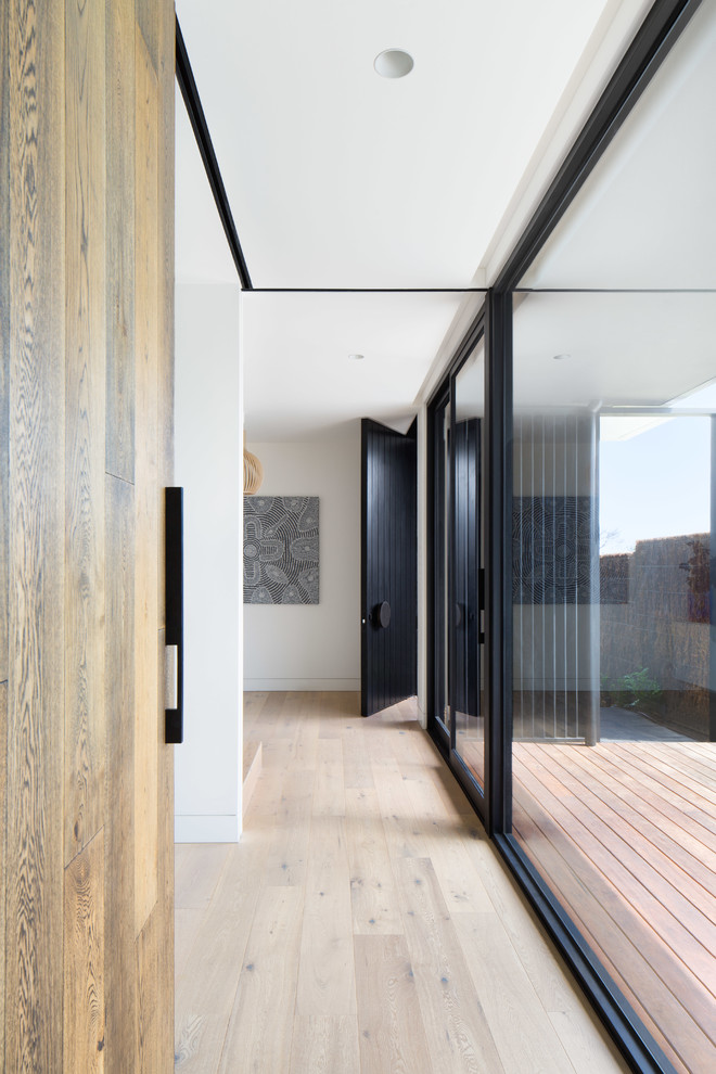 Example of a trendy light wood floor and beige floor hallway design in Melbourne with white walls