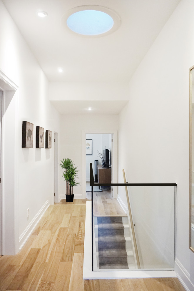 Modelo de recibidores y pasillos minimalistas pequeños con paredes blancas, suelo de madera en tonos medios y suelo marrón
