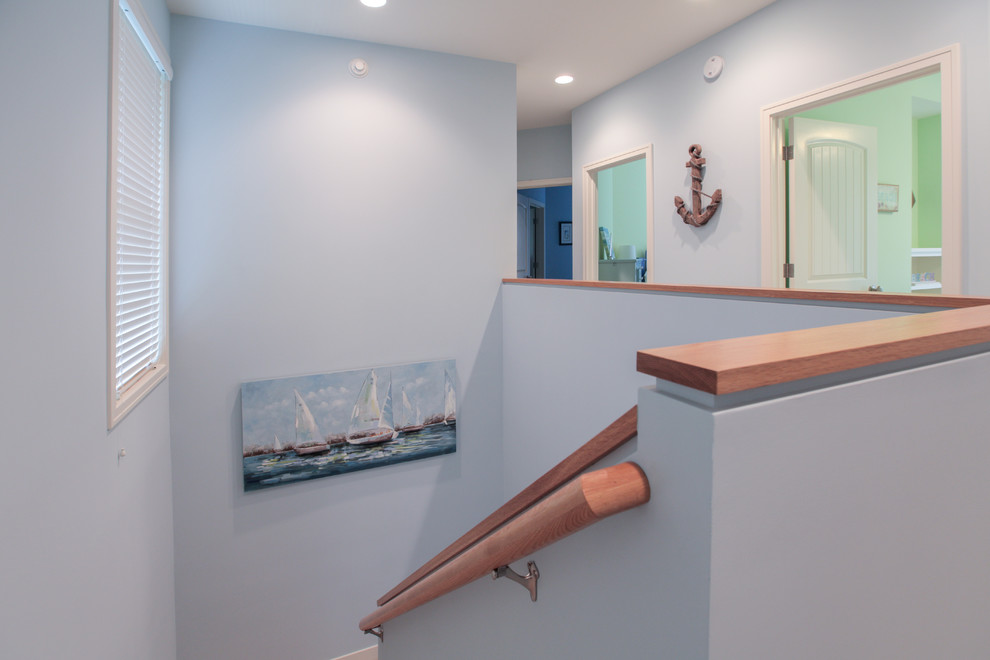 Example of a beach style light wood floor hallway design in Grand Rapids with blue walls