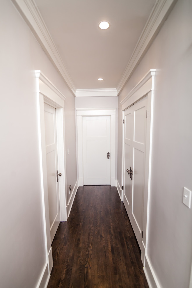Immagine di un piccolo ingresso o corridoio stile americano con pareti bianche, parquet scuro e pavimento marrone