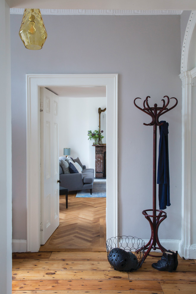 Idée de décoration pour un grand couloir tradition avec un mur gris et un sol en bois brun.