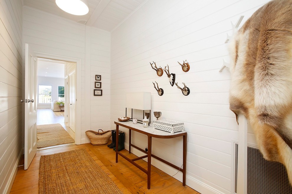 Idée de décoration pour un couloir champêtre de taille moyenne avec un mur blanc, parquet clair et un sol marron.