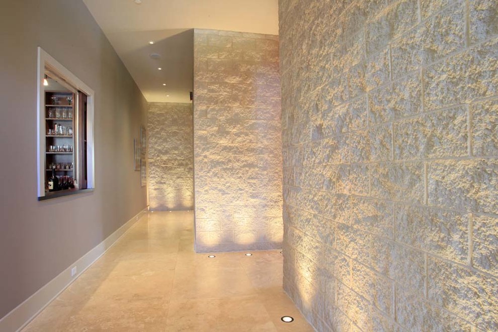 Cette image montre un grand couloir avec un mur blanc et un sol en travertin.